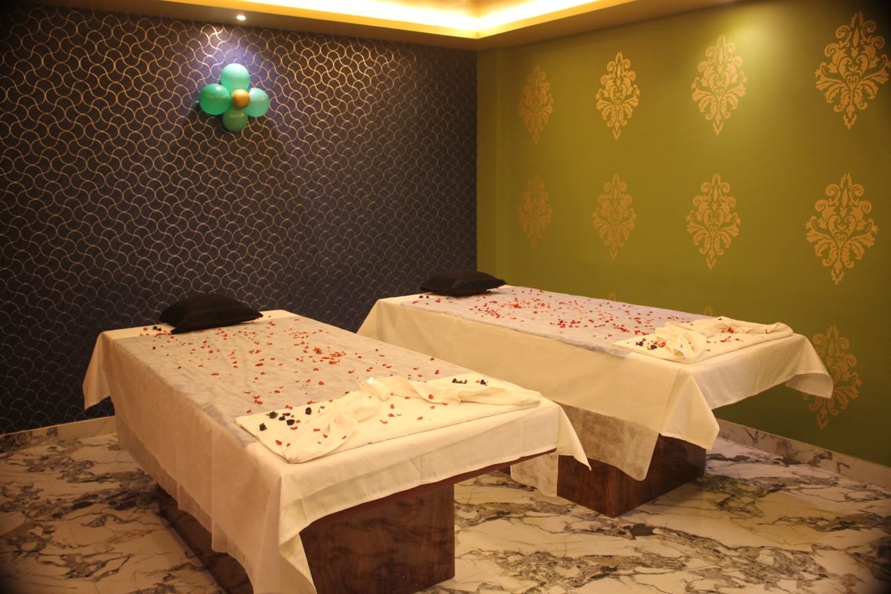 Couples treatment room at Dream Premium Spa in Bengaluru — two massage beds with rose petals and warm gold lighting